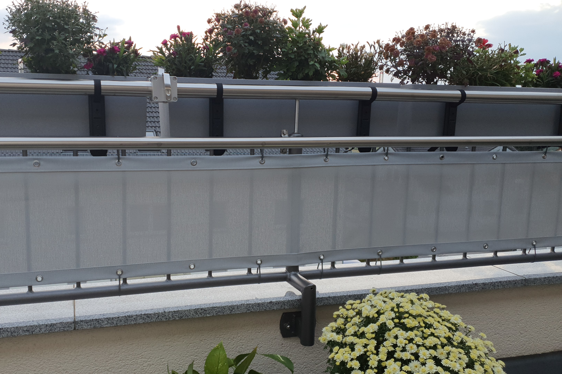 Ein Sonnensegel überdeckt eine Terasse und hüllt sie in ein angenehmes Licht