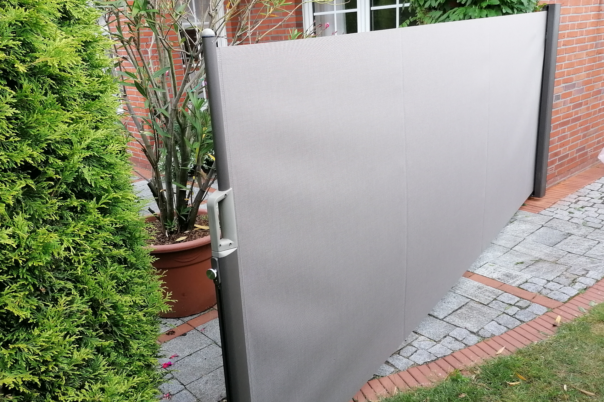 Ein Sonnensegel überdeckt eine Terasse und hüllt sie in ein angenehmes Licht