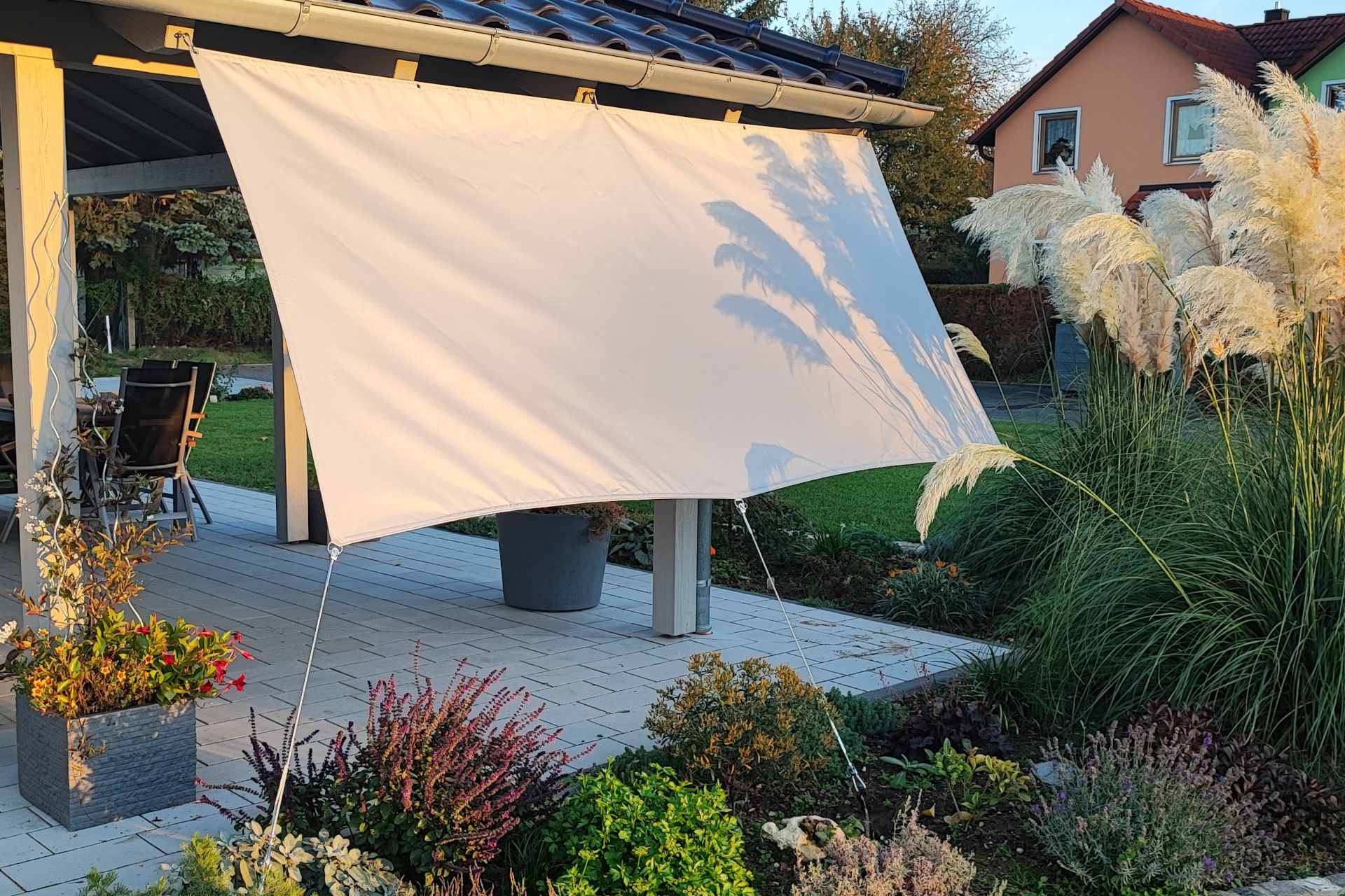 Ein Sonnensegel überdeckt eine Terasse und hüllt sie in ein angenehmes Licht